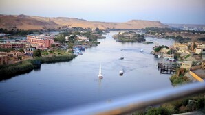 Un río con barcos, un velero y edificios a lo largo de la orilla.
