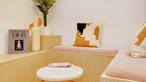 A cozy corner with a round table, a book titled "Christian Dior", a potted plant, and a cushioned bench with patterned pillows. - Amazing Studio - 2P - Arc de Triomphe (Paris)
