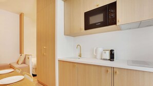 A compact kitchen with a microwave, coffee maker, and a white countertop. - Amazing Studio - 2P - Arc de Triomphe (Paris)