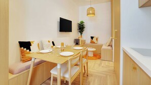 A modern dining area with a wooden table, white chairs, and a small side table with a plant. - Amazing Studio - 2P - Arc de Triomphe (Paris)
