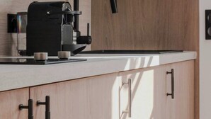 Una cocina moderna con cafetera integrada, armarios de madera y una encimera elegante.