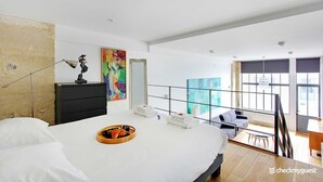 Una habitación de hotel moderna con una cama grande, un escritorio y un balcón con vistas.