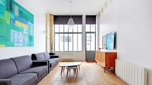 Una sala de estar moderna con un sofá gris, una mesita redonda y un mueble de madera.