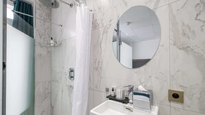 A modern bathroom with a shower, a sink, a mirror, and a towel rack. - Hotel Avaton - Deluxe Bedroom Balcony - Cannes Palais (Cannes)