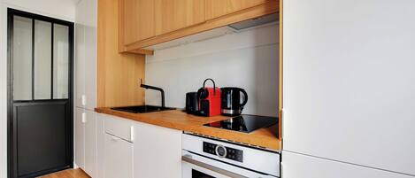 A modern kitchen with white cabinets, a wooden countertop, a Bosch oven, and a black coffee maker.
