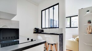 Une cuisine moderne avec un plan de travail noir, des chaises blanches et une grande fenêtre.