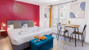 Una habitación de hotel moderna con una cama grande, una mesa de comedor y un balcón con vistas.
