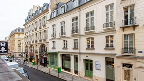Vista de una calle con una hilera de edificios de estilo europeo, varios pisos, balcones y tiendas en la planta baja.