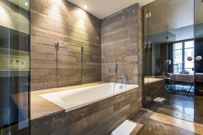 A modern bathroom with a large bathtub, glass shower enclosure, and a view of the city through a large window. - Modern Apartment - 1br/4p - Passy (Paris)