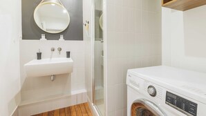 Egy modern fürdőszoba mosdókagylóval, tükörrel és mosógéppel.