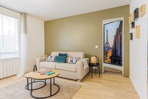 Ein Wohnzimmer mit einer Couch, einem Couchtisch und Blick auf eine Stadtlandschaft durch eine Tür.