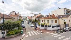 Une rue résidentielle bordée de maisons, avec des voitures garées et un passage piéton.