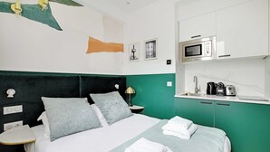 Hotellihuone, jossa on sänky, yöpöytä, lamppu, mikroaaltouuni ja pesuallas.
