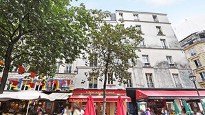 An outdoor café with red umbrellas and a banner reading "La Baguette du Relais." - Chic Studio A/C - 2P - Le Marais (Paris)