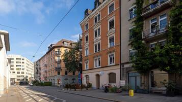 A street view with multi-story buildings, a tram line, and a clear sky.