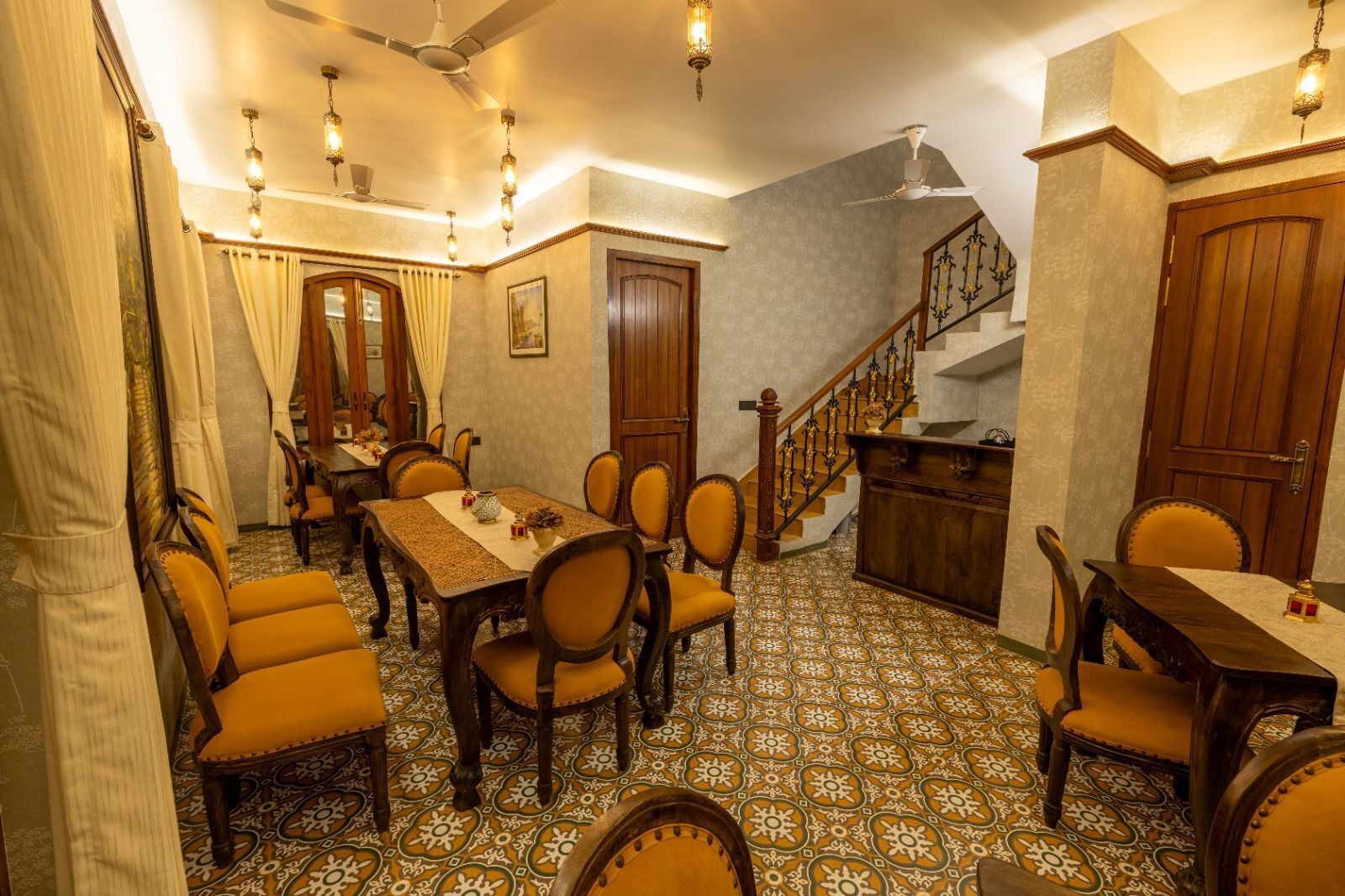 Un espace repas comprenant une longue table, plusieurs chaises, un escalier et un buffet en bois.