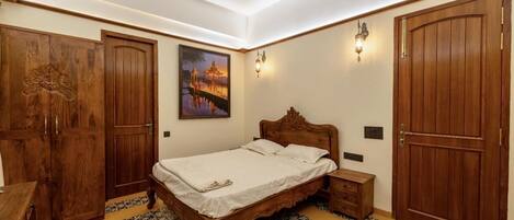 Un dormitorio con cama de madera, una mesita de noche, un armario y un cuadro en la pared.