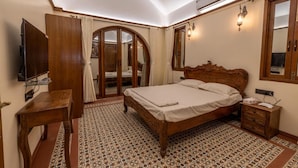 A bedroom with a wooden bed, a bedside table, a TV, and a wardrobe. - Ishaan Holiday Home (Alibag)