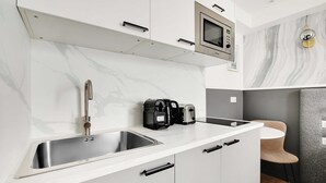 A modern kitchen with a stainless steel sink, a microwave, and a coffee maker on the countertop. - Cosy Studio With Air Conditioning -near Montmartre (Paris)