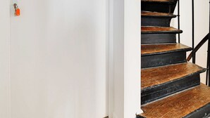 A white door with a numeric keypad and a keyhole, leading to a black spiral staircase with wooden steps. - Cosy Studio With Air Conditioning -near Montmartre (Paris)