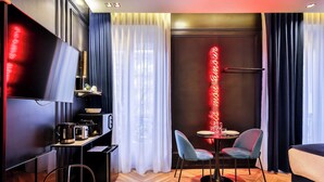 A modern hotel room with a flat-screen TV, a small kitchenette, a dining area with two chairs, a sofa, and a neon sign on the wall. - Wonderful Private Room - 2P - Chatelet (Paris)