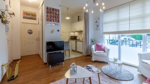 A modern living room with a flat-screen TV, a dining area, and a kitchen. - Cosy Studio - 2P - Port de Deauville (Deauville)