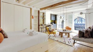 Een kamer met een bed, een eettafel, een bank en een keukenhoek.