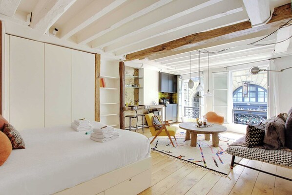 A room with a bed, a dining table, a sofa, and a kitchen area. - Appartement in the Heart of Paris Saint Germain (Paris)