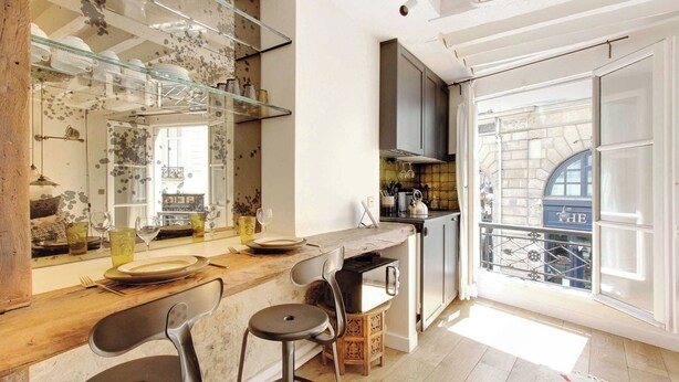 Een moderne keuken met een groot raam, een bar met krukken, en een rustieke houten toonbank.