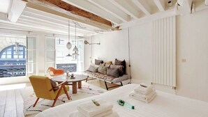 Een moderne slaapkamer met een bed, een slaapbank, een eettafel en uitzicht op de stad.