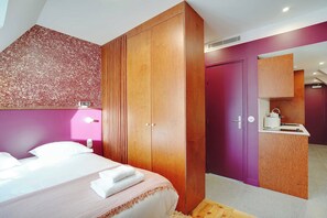 A bedroom with a bed, wooden wardrobe, and a bathroom with a sink and mirror. - Elegant Studio - 2P - Republique (Paris)