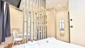 Una habitación de hotel con cama, una silla, un escritorio y televisor.