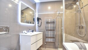 Un baño moderno con cabina de ducha de vidrio, tocador empotrado con espejo y toallero calefactable.