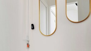 A white door with a number plate, a gold-framed mirror, and a gold-framed console table.