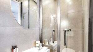 A modern bathroom with a glass-enclosed shower, a white sink, and a mirror above it.
