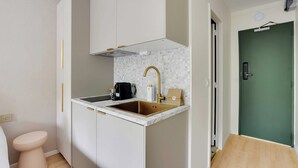 A compact kitchen with a sink, countertop, and a green door in the background. - Modern "green Suites" Residence - Meudon/velizy (Meudon)