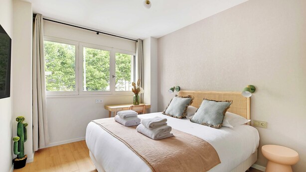 A bedroom with a large bed, a bedside table, a nightstand, a window, and a cactus plant. - Modern "green Suites" Residence - Meudon/velizy (Meudon)