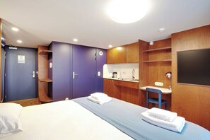 A hotel room with a bed, a desk, a chair, and a wardrobe. - Magnificent Studio - 2P - Republique (Paris)