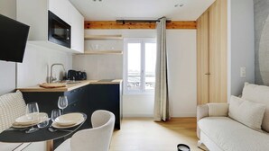 A modern kitchen with a microwave, coffee maker, and dining area with a table set for four. - Cosy Studio With AC -2p- Sacra-coeur Montmartre (Paris)
