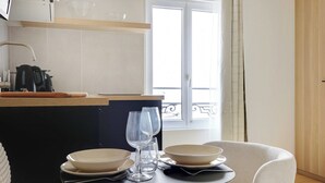 A modern kitchen with a dining table set for two, featuring a coffee machine, a kettle, and a bowl. - Cosy Studio With AC -2p- Sacra-coeur Montmartre (Paris)