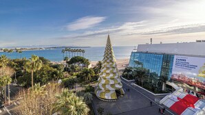 Una gran estructura cónica con diseño espiral, un edificio moderno con fachada de vidrio, y una playa al fondo.