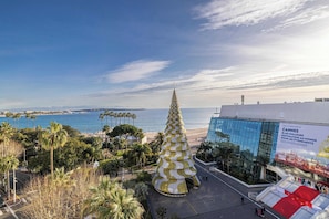 A large conical structure with a spiral design, a modern building with a glass facade, and a beach in the background.