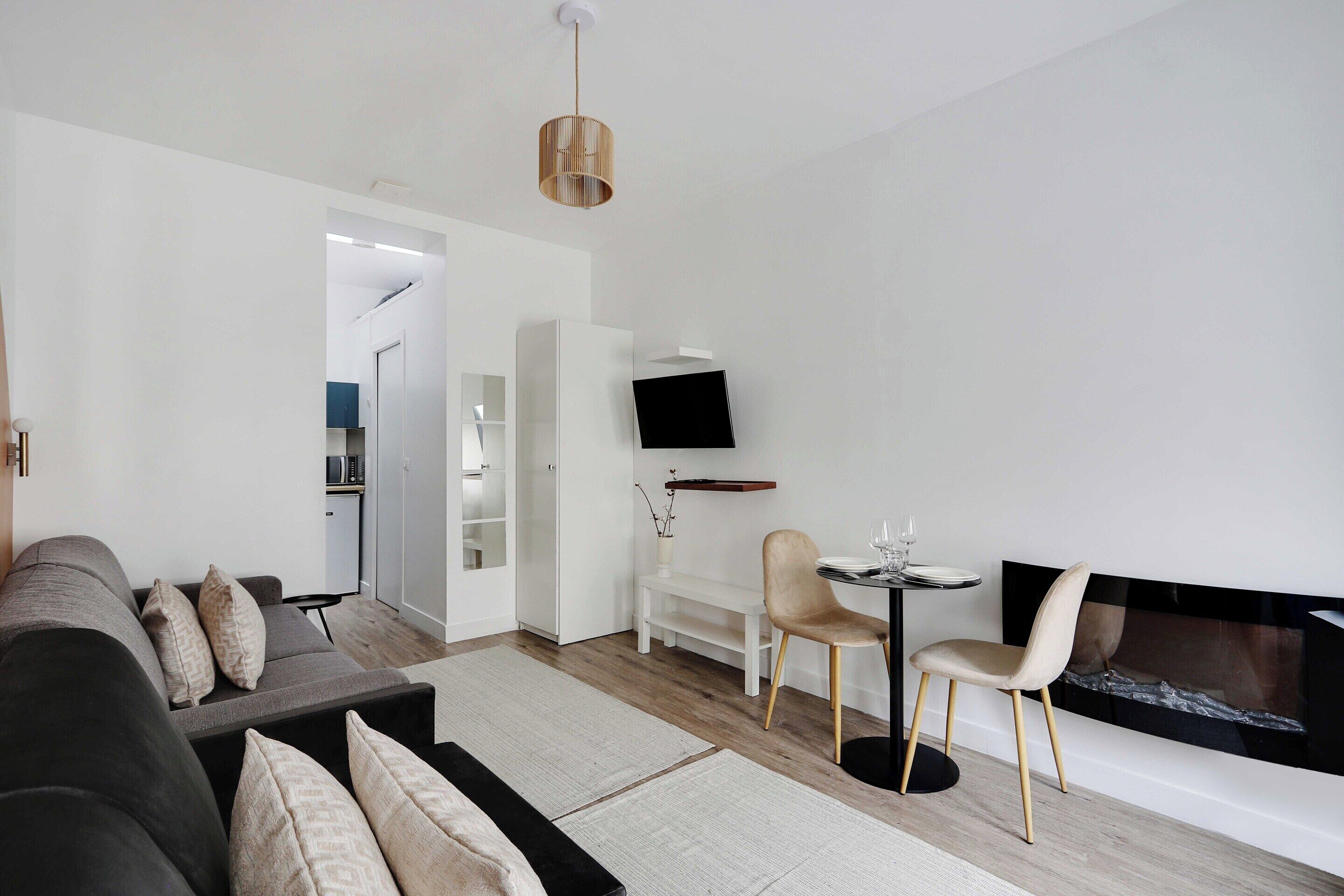 Un salon moderne avec un canapé, des fauteuils, une cheminée et un téléviseur fixé au mur.