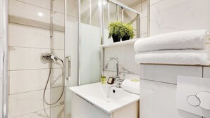 A modern bathroom with a glass shower enclosure, a white sink, and a mirror above it. - Magnificent Studio - 2P - Near Bastille (Paris)