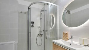 Un bagno moderno con doccia vetrata, un lavandino bianco con mobile in legno e uno specchio grande.