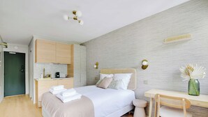 Una camera da letto moderna con un letto, un comodino, una sedia e un angolo cottura.