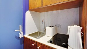 A compact kitchen with a sink, a toaster, and an induction cooktop. - Cosy Studio - 2P - Folie-mericourt (Paris)