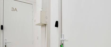 A hallway with doors labeled 3A and 3B, a green exit sign, and a security camera.