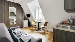 Un moderno loft con comedor, kitchenette y un amplio ventanal que proporciona luz natural.