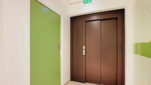 A hallway with a green door and a brown elevator door. - Studio Sleek & Refined - Levallois-perret (Levallois-Perret)